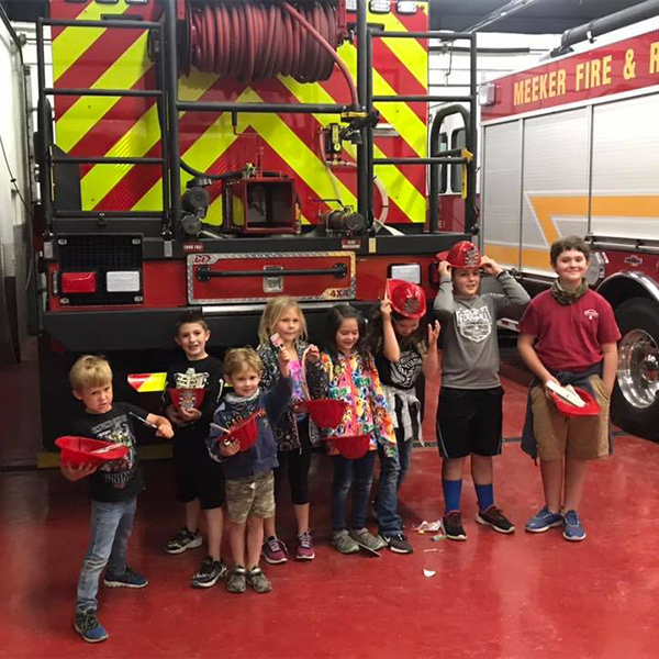 A group of school children touring the fire department with a large firetruck in a bay